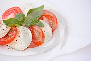 Fresh Italian Caprese Salad with Mozzarella Cheese, Tomatoes and Basil on white plate. Healthy food concept