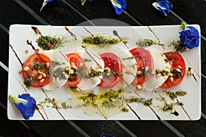 Fresh Italian Caprese salad with mozzarella, tomatoes and green basil leaves on white plate