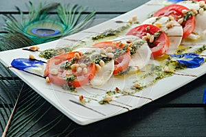 Fresh Italian Caprese salad with mozzarella, tomatoes and green basil leaves on white plate