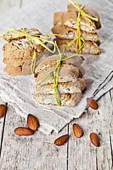 Fresh Italian cookies cantuccini stacks and almond nuts on linen napkin on ructic wooden table background