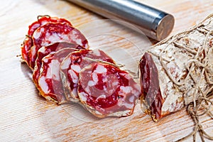 Fresh italian piacenza salami cut in slices on a wooden surface