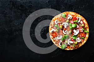 Fresh italian pizza with mushrooms, ham, tomatoes, cheese, olive, basil on black concrete background, rustic table. Copy photo