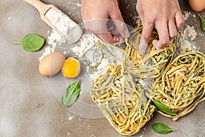 Fresh italian uncooked homemade pasta. Hands making pasta tagliatelle. Raw homemade spinach pasta