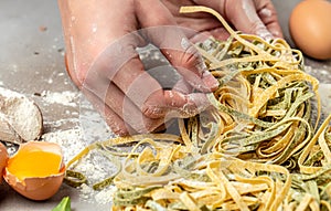 Fresh italian uncooked homemade pasta. Hands making pasta tagliatelle. Raw homemade spinach pasta