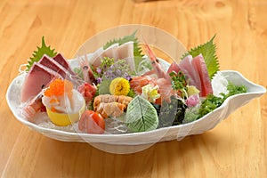 Fresh Japanese food mixed Sashimi Moriawase platter with ice, fish slice a dish isolated on wooden background top