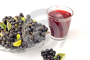 Fresh juice of black chokeberry Aronia melanocarpa in glass and beries in pot, isolated on white background