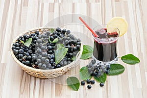 Fresh juice of chokeberry or Aronia melanocarpa in glass with ice, lemon and straw.