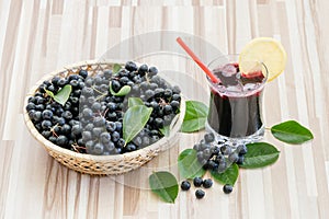 Fresh juice of chokeberry or Aronia melanocarpa in glass with ice, lemon and straw. photo