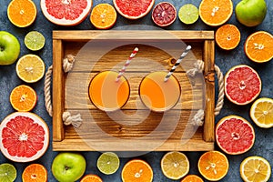 Fresh juice or smoothie with organic citrus fruit, apple, grapefruit on light background. Top view, selective focus