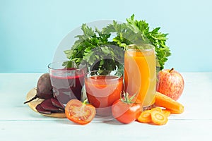 Fresh juice smoothies from a variety of vegetables beetroot apple carrot tomatoes in glasses on wooden blue background