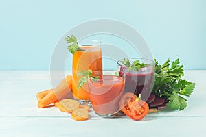 Fresh juice smoothies from a variety of vegetables beetroot apple carrot tomatoes in glasses on wooden blue background