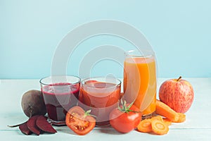 Fresh juice smoothies from a variety of vegetables beetroot apple carrot tomatoes in glasses on wooden blue background.