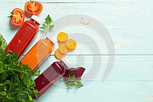 Fresh juice smoothies from a variety of vegetables carrots apple tomatoes beets in bottles on a wooden blue background