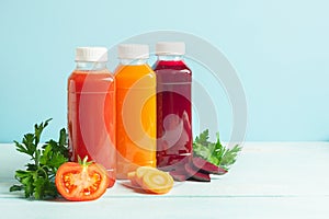 Fresh juice smoothies from a variety of vegetables carrots apple tomatoes beets in bottles on a wooden blue background