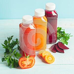 Fresh juice smoothies from a variety of vegetables carrots apple tomatoes beets in bottles on a wooden blue background