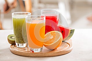 Fresh juices smoothie three glass red green orange tropical fruits water melon, kiwi, orange. Selective focus