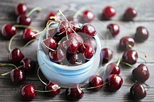Fresh juicy cherries in a blue bowl on a gray wooden background. Cherry closeup in a bowl. Berries in drops of water. Food