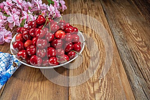 Fresh, juicy cherries in a plate on a wooden table close-up, rustic style