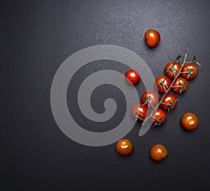 Fresh juicy cherry tomatoes on a branch on the chalkboard border ,place for text wooden rustic background top view