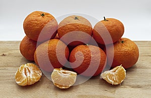 Fresh juicy clementine mandarins on wooden table, white background.