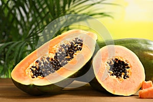 Fresh juicy cut papayas on wooden table against blurred background