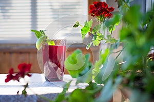 A fresh juicy glass of fruit and berry drink stands on a round table with a linen bright tablecloth