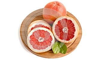 Fresh juicy grapefruit whole and sliced with leaves on a kitchen wooden board.White isolated background.Top view.