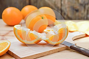 Fresh and juicy half and slice of orange fruit on a chopping block on weathered wooden table background.