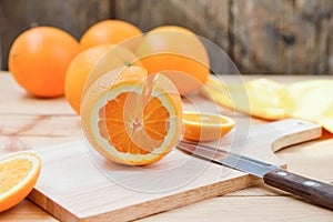 Fresh and juicy half and slice of orange fruit on a chopping block on weathered wooden table background.