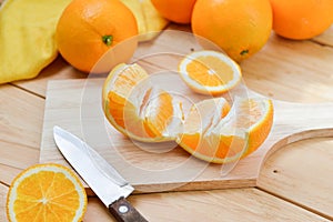 Fresh and juicy half and slice of orange fruit on a chopping block on weathered wooden table background.