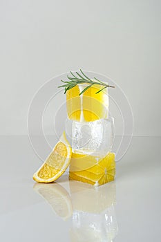 Fresh juicy lemon and ice cube stacked on top of each other and branch of rosemary. Trendy lemonade concept photo