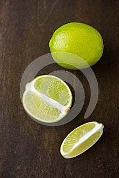 Fresh juicy limes on dark wooden background