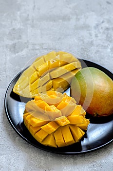Fresh juicy mango cut on a black plate