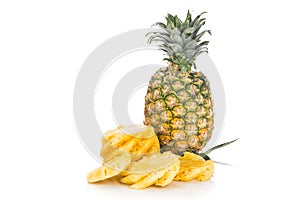 Fresh juicy nutritious cut pineapple with whole fruit as backgro