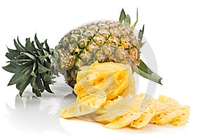 Fresh juicy nutritious cut pineapple with whole fruit as backgro