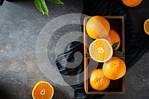 Fresh juicy oranges in a basket or box. Oranges on dark stone background. Pile of oranges top view, copy space. Healthy clean