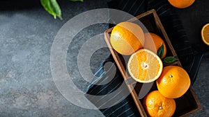 Fresh juicy oranges in a basket or box. Oranges on dark stone background. Pile of oranges top view, copy space. Healthy clean