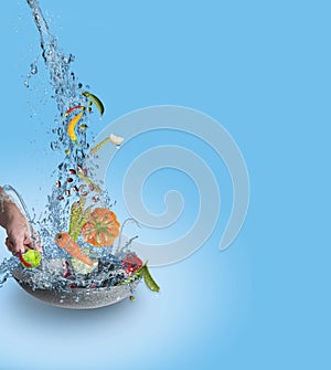 Fresh juicy organic vegetables fall into the pan with water splash  on blue gradienten background.