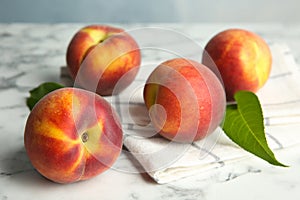 Fresh juicy peaches, leaves and fabric on table