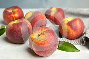 Fresh juicy peaches, leaves and fabric on wooden table