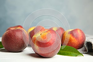Fresh juicy peaches, leaves and fabric on white table