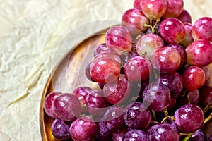 Fresh juicy pink and purple grape berries ripe in a bunch on wooden background.