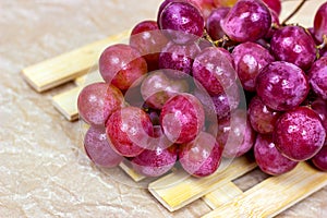 Fresh juicy pink and purple grape berries ripe in a bunch on wooden background.