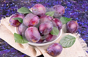 Fresh juicy plums in a bowl on a dark blue background. Close-up.