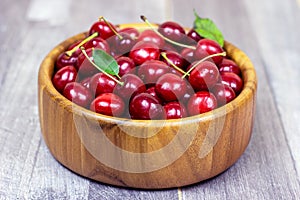 Fresh juicy red sweet cherry berries in the wooden bowl on light background in summer.