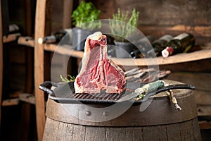 Fresh, juicy seasoned t-bone steak in a standing position on a grill pan with a hunting knife next to it, in the restaurant