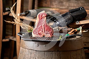 Fresh, juicy seasoned t-bone steak in a standing position on a grill pan with a hunting knife next to it, in the restaurant