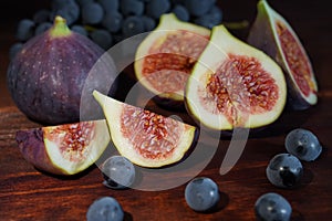 Fresh juicy sliced figs with grape on brown wooden table