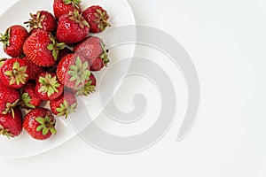 Fresh juicy strawberries on white plate, served with cutlery, is