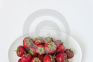 Fresh juicy strawberries on white plate, served with cutlery, is